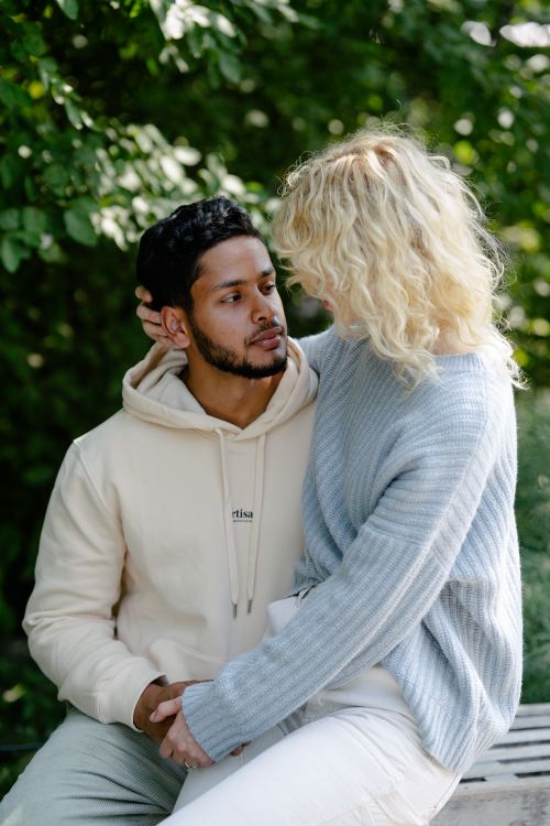 Free A loving couple shares an intimate moment on a park bench surrounded by greenery. Stock Photo