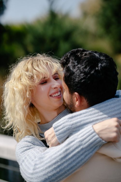 Free Happy couple embracing each other in a sunny outdoor setting, enjoying a warm moment together. Stock Photo