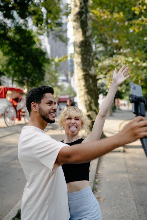 Free Joyful couple posing for a fun selfie in a sunny park setting. Stock Photo