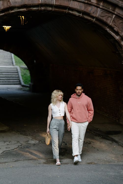 Free A couple walking hand in hand through a stone tunnel during the day. Stock Photo