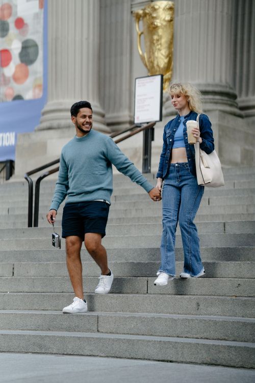 Free Happy couple holding hands while walking down city steps. Casual and cheerful moment. Stock Photo