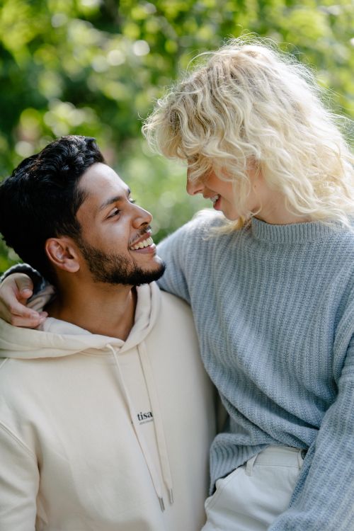 Free A couple enjoying a tender moment outdoors, surrounded by greenery and love. Stock Photo
