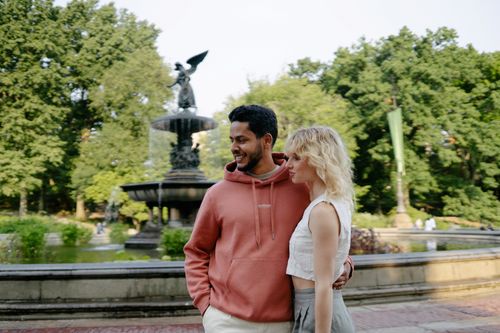 Free Smiling couple in a park by a fountain, enjoying a warm day outdoors. Stock Photo