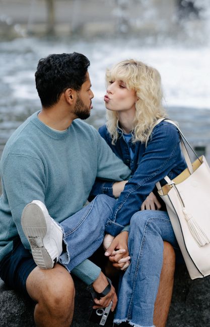 A young couple seated near a fountain, gazing at each other with affection.