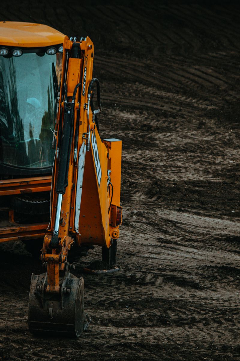 Close-up of a yellow excavator on a construction site with muddy terrain