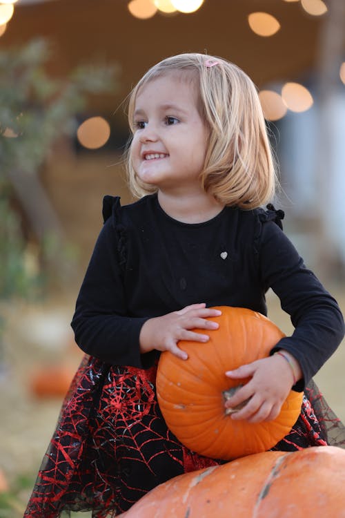 Free Girl in Black Long Sleeved Shirt Holding Pumpkin Stock Photo