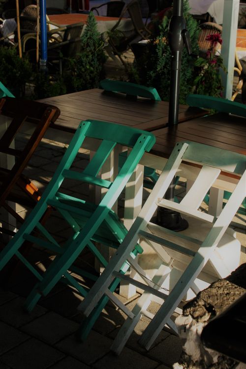 Free Sunlit arrangement of colorful wooden chairs in an outdoor café with tables. Stock Photo
