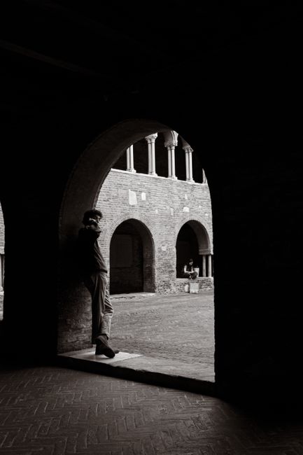 Artistic black and white photograph of a man in an archway, capturing architectural elegance.