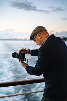 A man in black long sleeves photographing the Bosphorus at twilight in Istanbul, Türkiye.