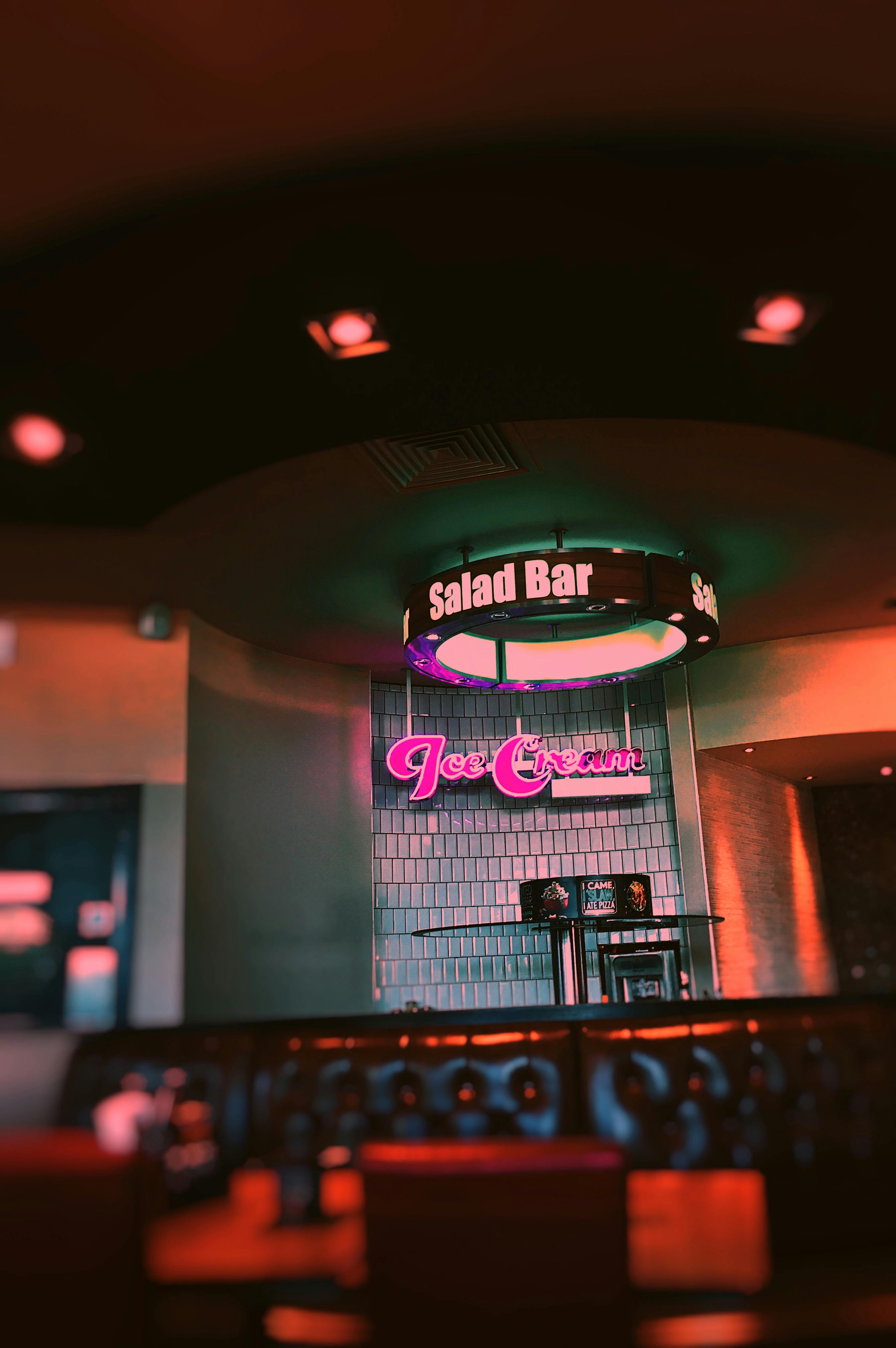 Free Warm-lit restaurant interior with an illuminated salad bar and ice cream sign. Stock Photo