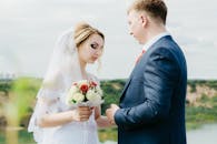 身着婚纱的新娘和新郎手持花束，在户外拍摄了一幅美丽的肖像