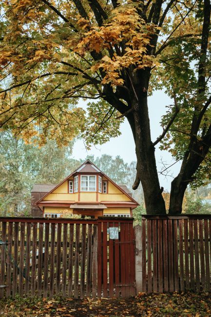 Picturesque wooden cottage in a serene forest, surrounded by autumn foliage.