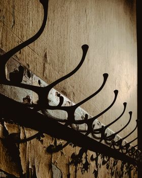 Row of antique coat hangers on a chipped wall, creating a rustic, textured look.