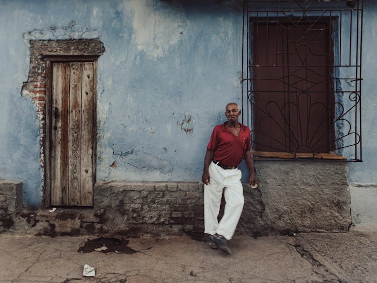 Man Standing On Street Under Chipped Wall