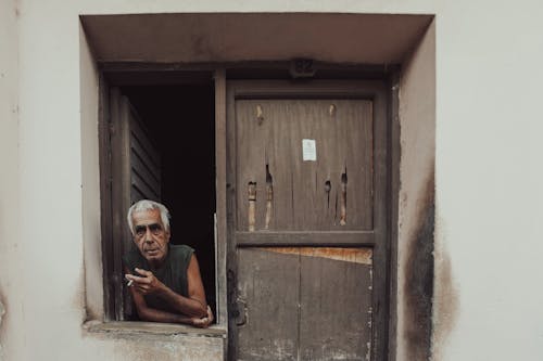 Man Smoking in Window by Wooden Door