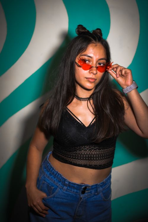 Free Fashionable young woman in vibrant outfit posing against patterned wall in Mexico City. Stock Photo
