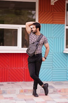 Young man in casual attire poses confidently against a vibrant, patterned wall.