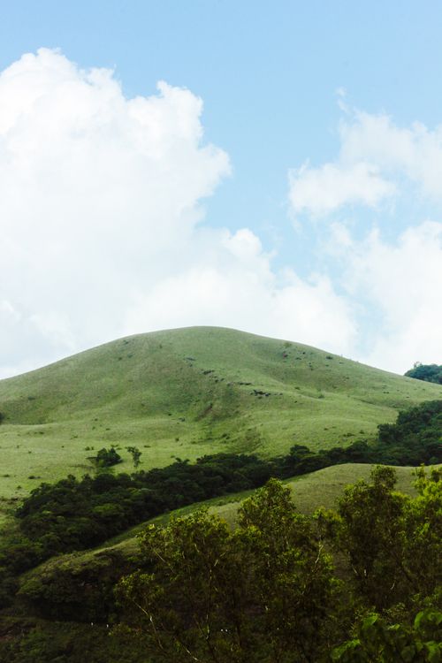 Free Lush green hills beneath a vibrant blue sky with fluffy clouds, perfect for countryside landscapes. Stock Photo