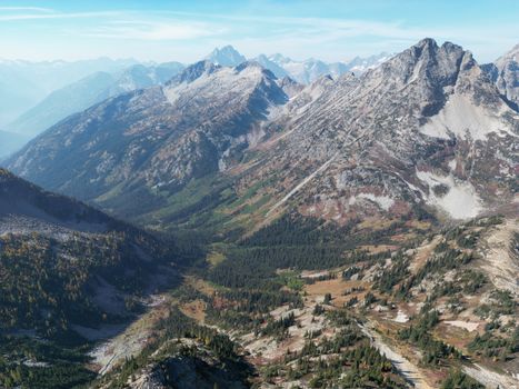 Discover the stunning aerial view of rocky mountains under a clear blue sky.