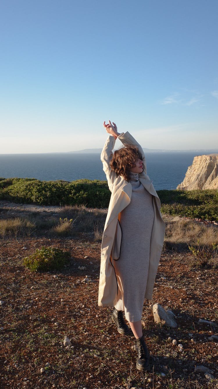 A Woman In Beige Trench Coat Wearing Turtleneck Dress While Looking Afar