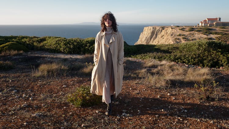 Wavy Haired Woman In Turtleneck Dress And Beige Coat 