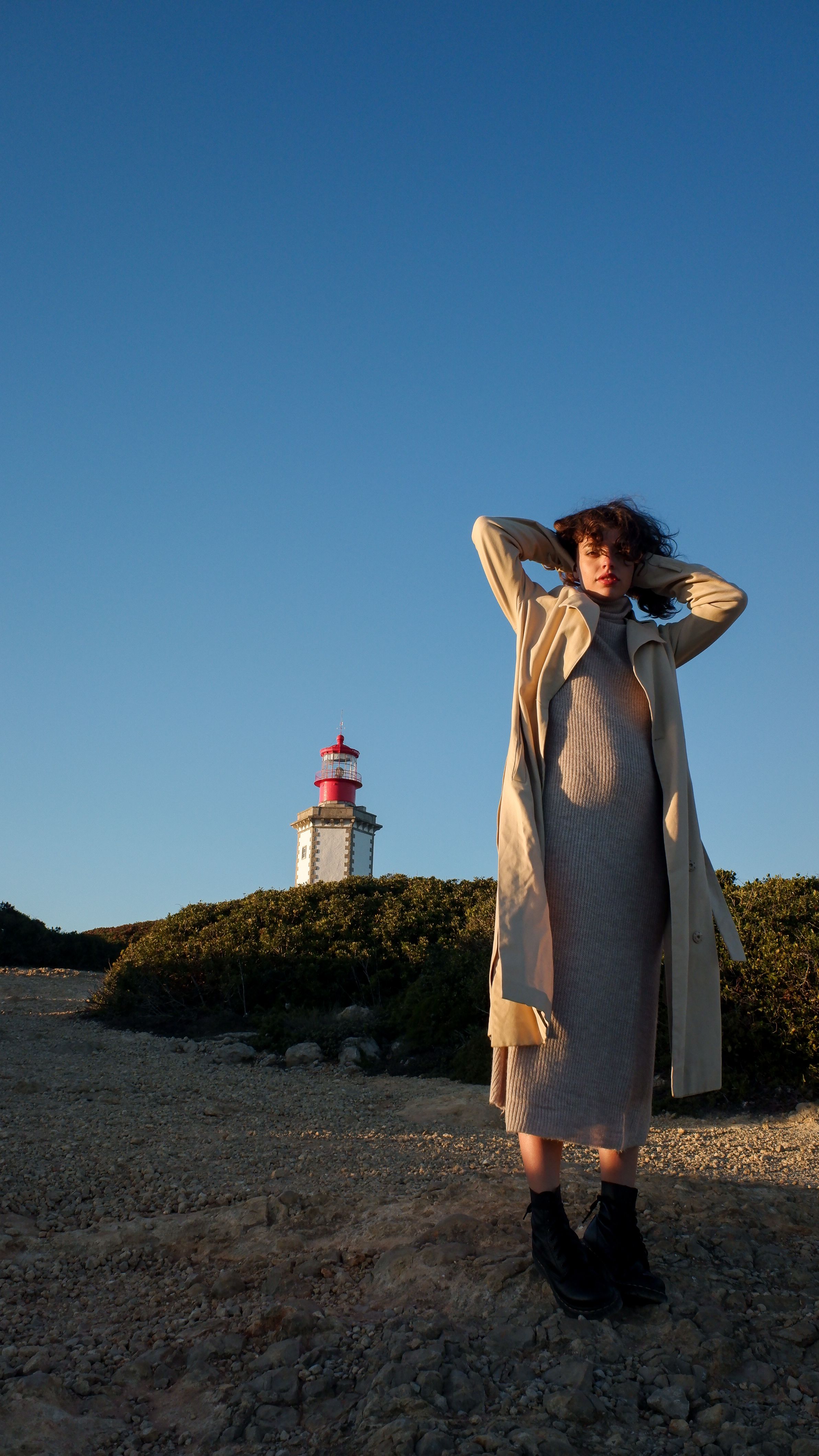A Woman in Beige Trench Coat Standing Near Lighthouse · Free Stock Photo