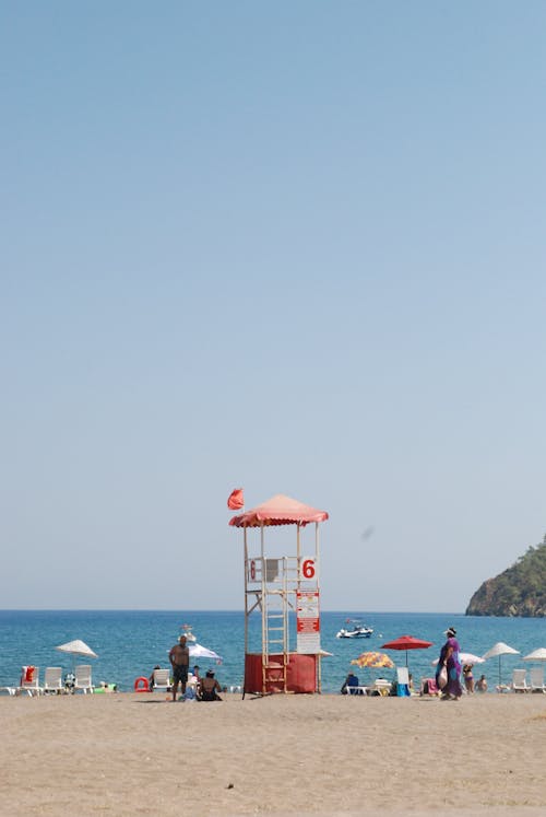 Free Sandy Beach with Sunshades and Lifeguard Tower Stock Photo