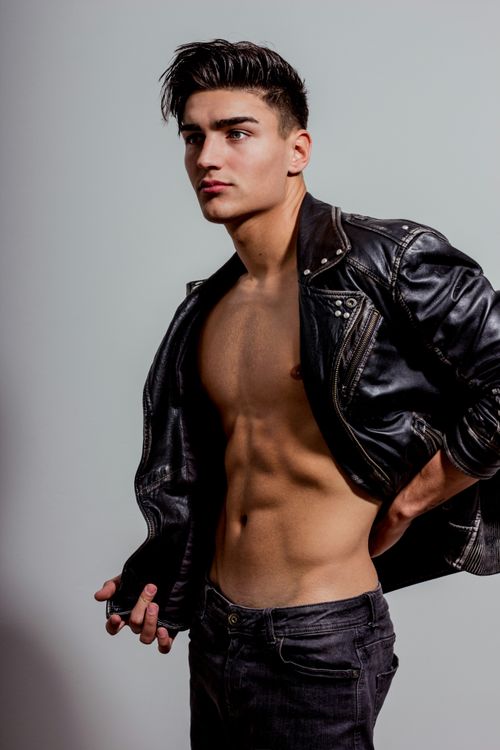 Free Handsome young male model posing in a leather jacket, showcasing a cool and fashionable look. Stock Photo