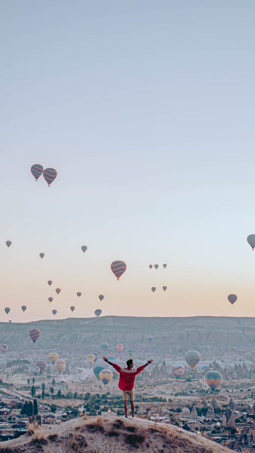 A Man Standing on the Hill Looking at the Hot Air Balloons