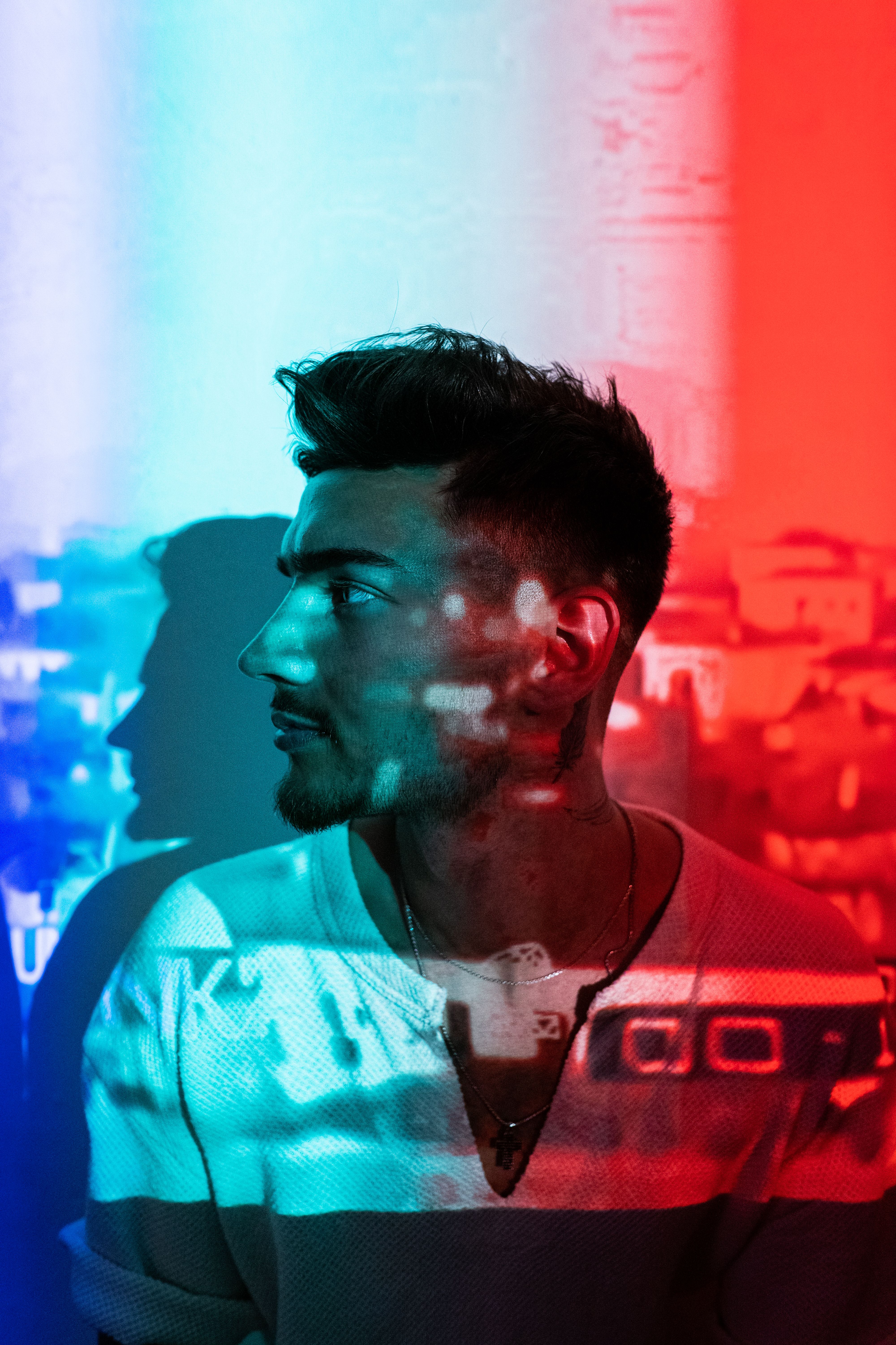 Side view of a man in Tirana with colorful light patterns projected on him, creating a vivid portrait.