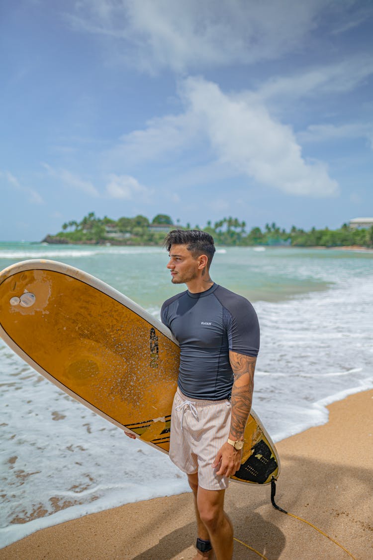 Man Holding A Surfboard At The Beach