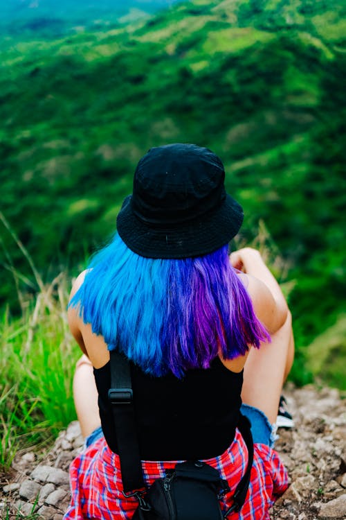 A Woman with Colorful Hair Wearing Bucket Hat while Sitting on Big Rock