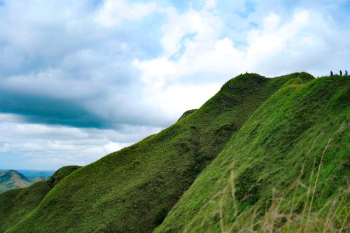 Free Lush green hills against a blue sky with scattered clouds, depicting natural beauty. Stock Photo