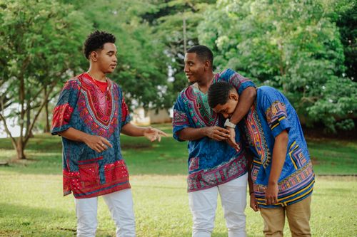 Free Three young men wearing colorful dashikis bonding outdoors in a lush park. Stock Photo