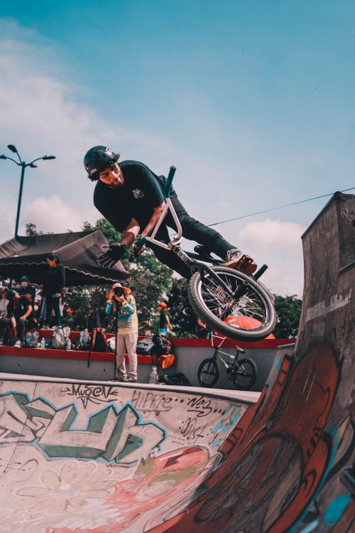 Free Dynamic BMX biker performing a freestyle trick at a vibrant urban skatepark. Stock Photo