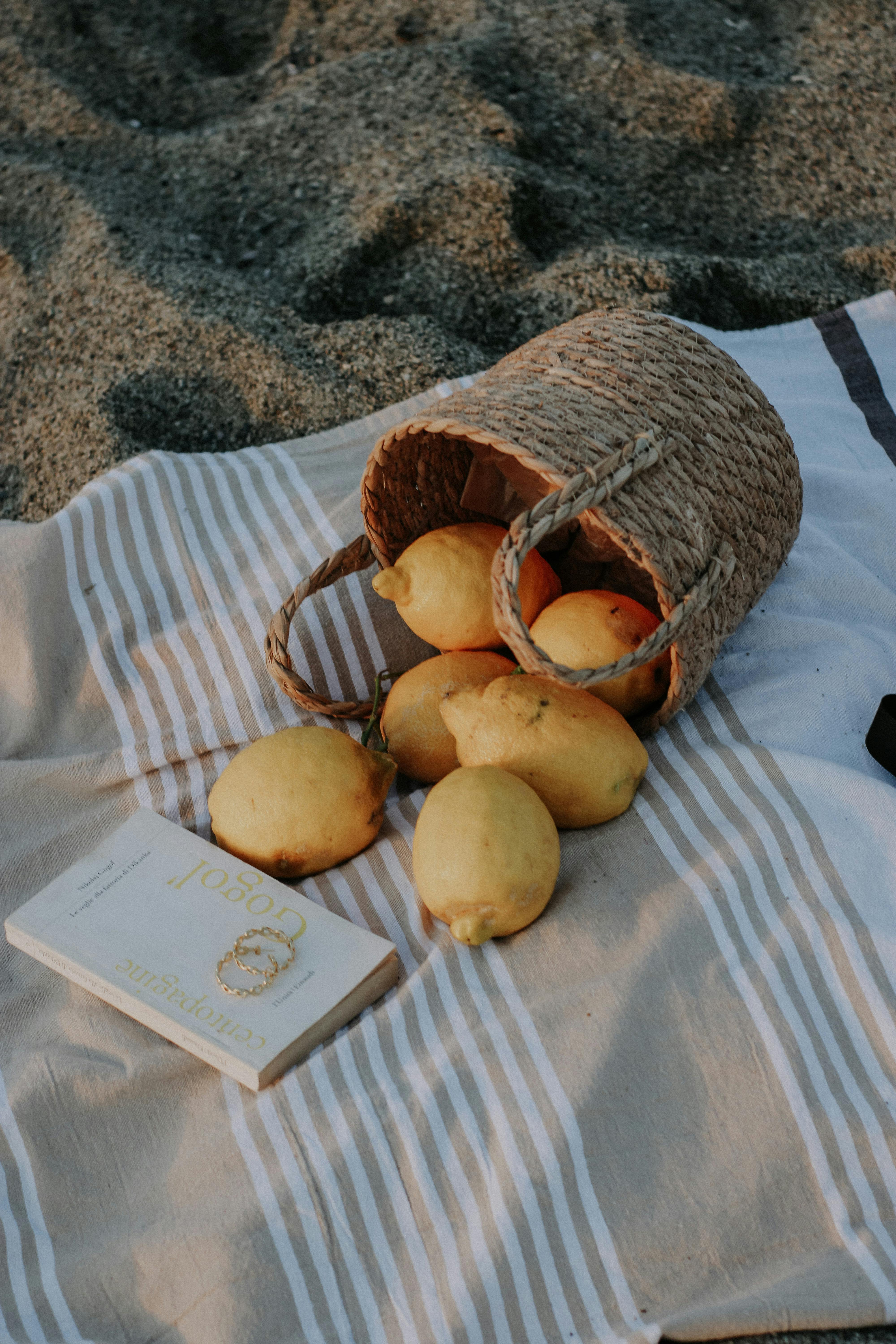 Seaside picnic with lemons spilling from a basket onto a striped blanket.