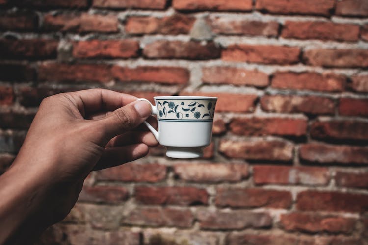 Hand Holding A White Ceramic Teacup 