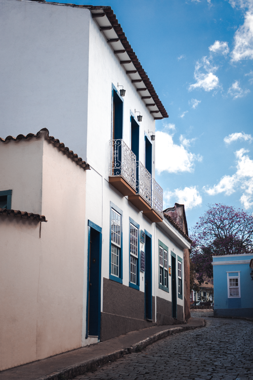 Free A picturesque colonial-style building on a cobblestone street under a bright blue sky. Stock Photo