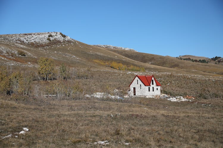 House In Field Surrounded By Trash