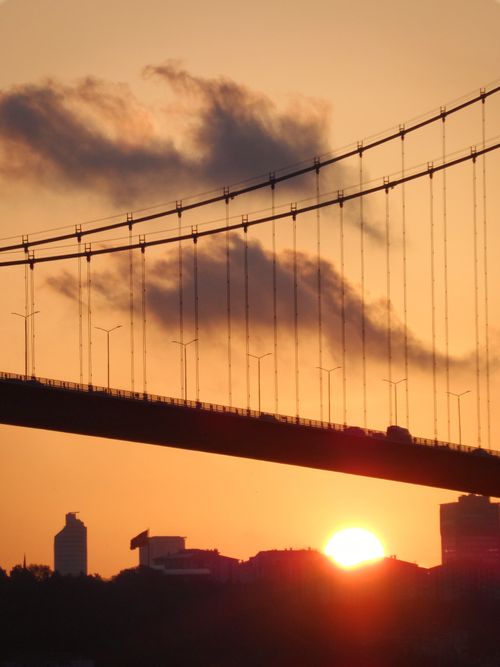 Free Dramatic silhouette of a bridge against a golden sunset with an orange sky. Stock Photo