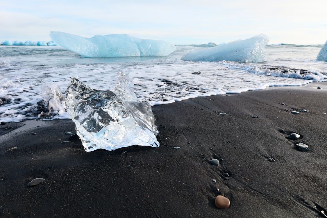 Sandy Shore with Waves and Floating Ice Chunks · Free Stock Photo