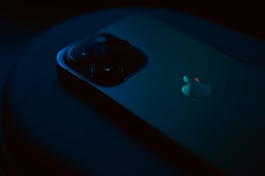 Close-up of a smartphone in dark lighting, highlighting its sleek design and camera lenses.