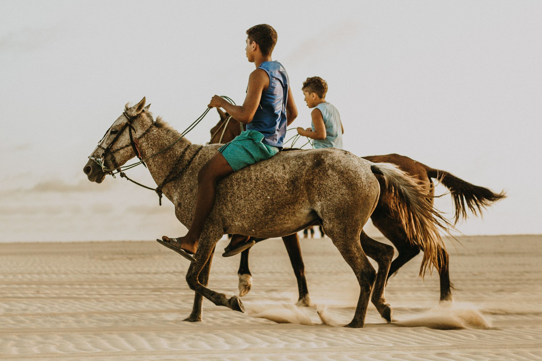 Kids riding horses on the sandy beach of Canoa Quebrada, Brazil. Captured in action at sunset.