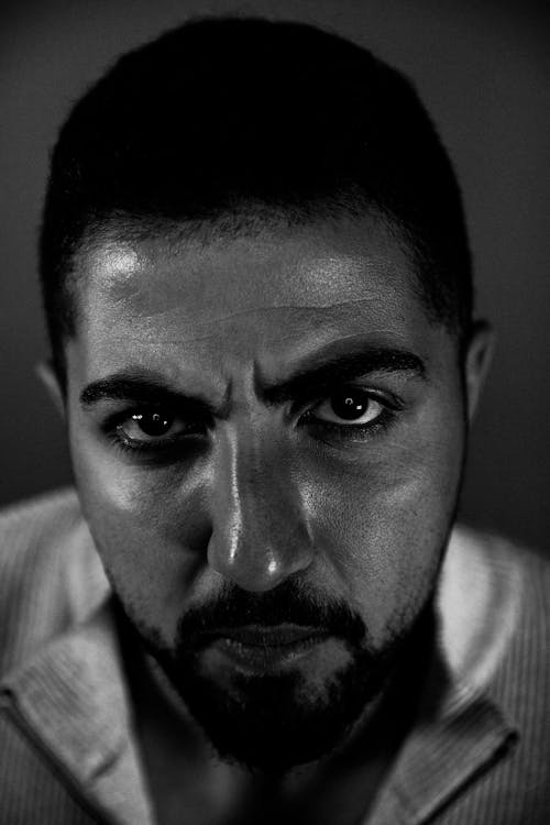 Grayscale Photography of a Bearded Man Seriously Looking at the Camera
