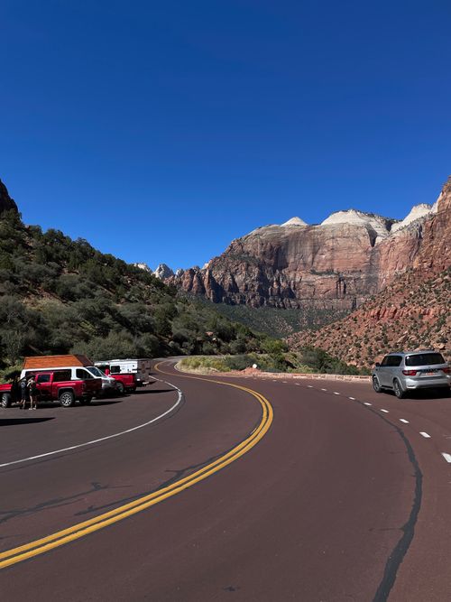 Free Curved road with parked cars and Zion Canyon mountains in background. Stock Photo