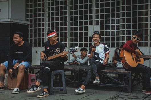 A group of young musicians enjoying a street performance in Jakarta with instruments.