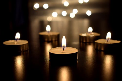 Free Atmospheric close-up of tea light candles glowing on a dark surface, creating a soft, warm ambiance. Stock Photo