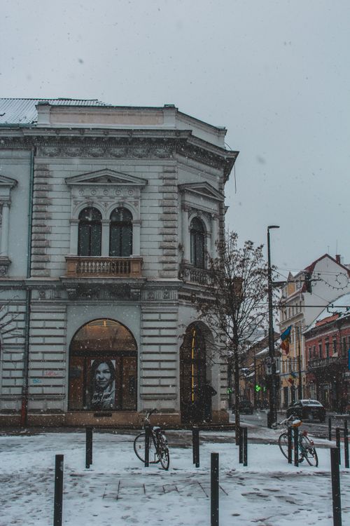 Free Snow falls on a historic urban street corner with parked bicycles and ornate architecture. Stock Photo