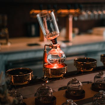 Elegant close-up of a siphon coffee maker with warm lighting in a cozy cafe setting.