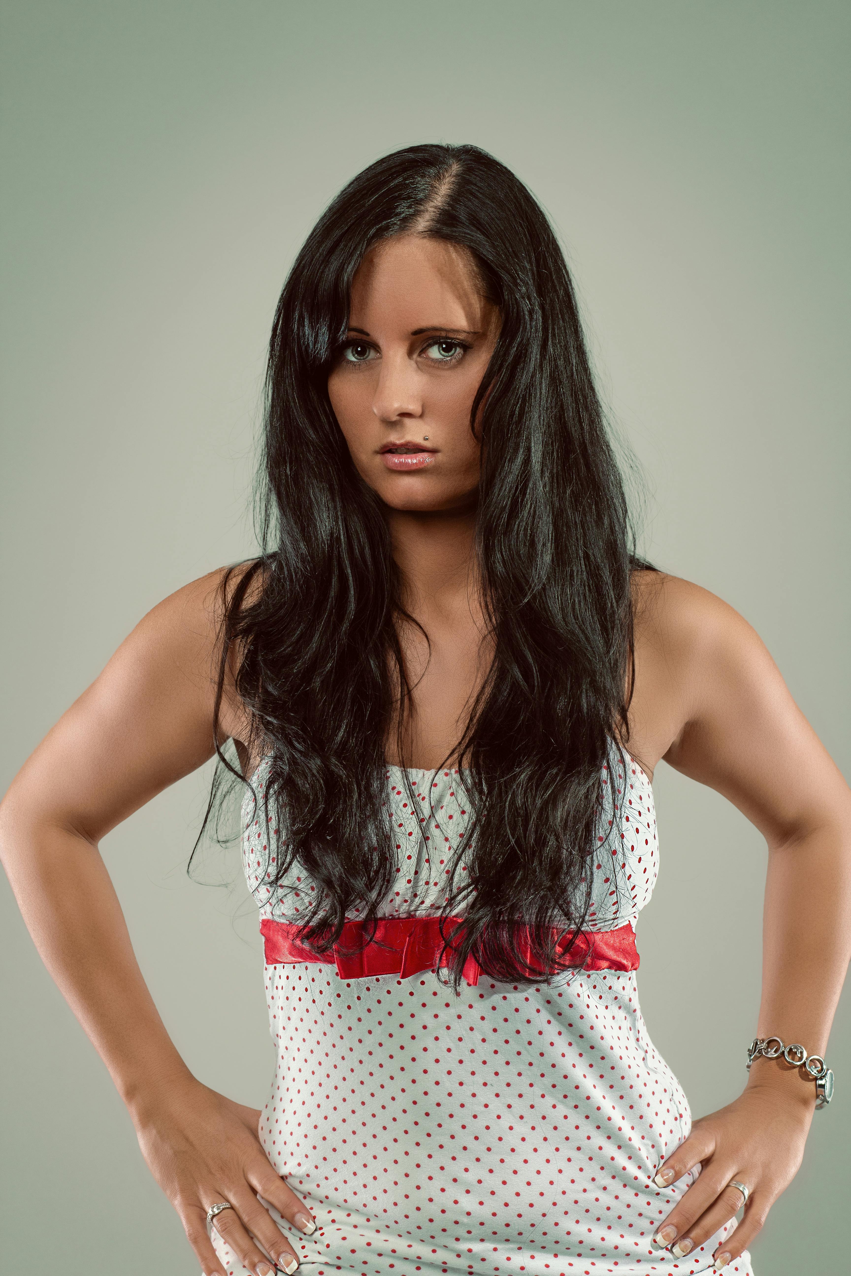 Portrait of a confident woman in a polka dot dress, captured in a studio setting.